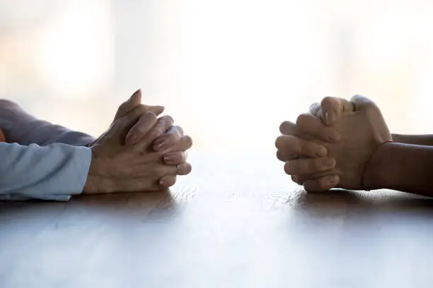 Photo of Close up clasped female hands of two businesswomen negotiate at table