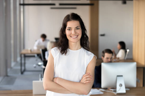 Head shot portrait of successful smiling businesswoman in office Head shot portrait of successful smiling businesswoman with arms crossed standing in office, looking at camera, happy female employee, team leader posing for company photo, beautiful woman at work saleswoman photos stock pictures, royalty-free photos & images