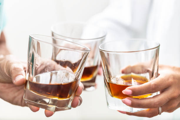 Group of friends toasting with glasses of whiskey brandy or rum indoors - closeup Group of friends toasting with glasses of whiskey brandy or rum indoors - closeup. alcohol abuse photos stock pictures, royalty-free photos & images