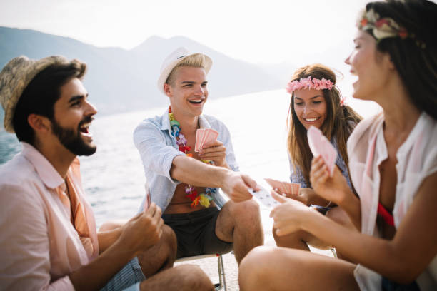 Group of friends having great time together on summer vacation Group of friends having great time together on the beach. friends playing cards stock pictures, royalty-free photos & images
