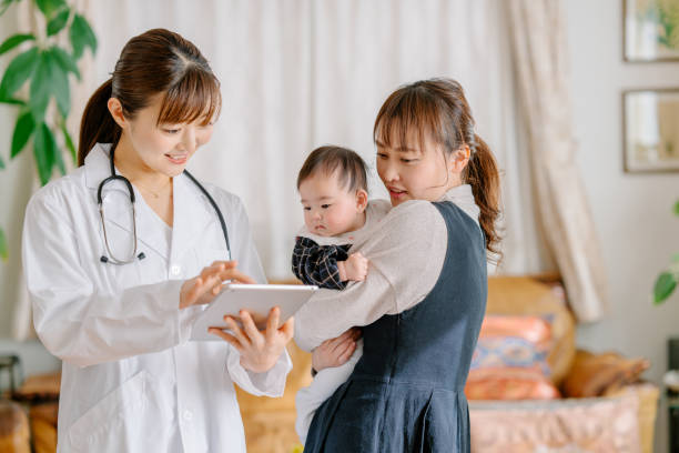 Pediatrician visiting young mum and her infant baby daughter in living room at home A pediatrician is visiting a young mum and her infant baby daughter in the living room at home. asian mom doctor visit witth kid stock pictures, royalty-free photos & images