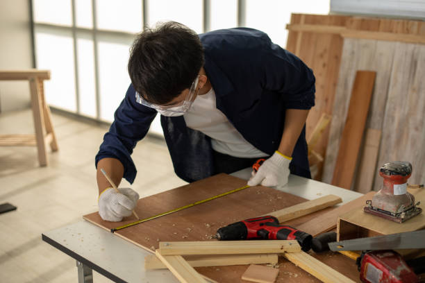 istock Asian man Carpenter working with technical drawing or blueprint construction paper lying on a workshop with carpentry tools and wood at home 1265501284