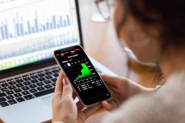 スマートフォンで金融チャートを分析する若い金融専門家 - 投資 ストックフォトと画像