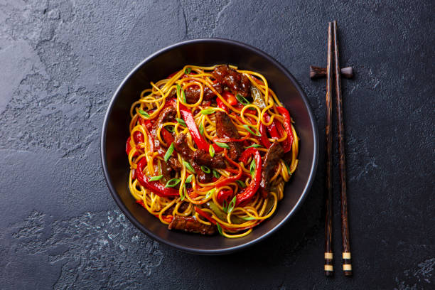 mescolare gli spaghetti friggere con verdure e manzo in una ciotola nera. sfondo ardesia. vista dall'alto. - chinese cuisine foto e immagini stock