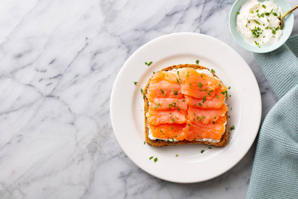 istock Sandwich, toast with smoked salmon and cream cheese on white plate. Marble background. Copy space. Top view. 1265520607