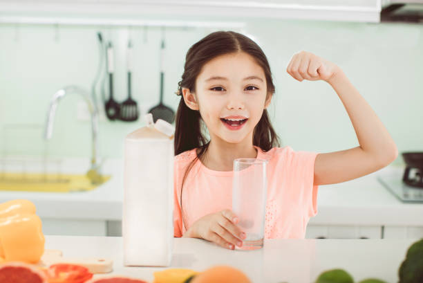 cute little girl drinking with milk at kitchen - milk child drinking little girls imagens e fotografias de stock