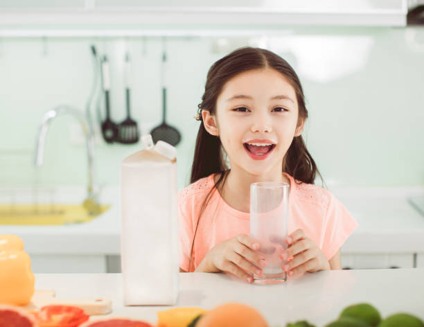 istock Cute little girl drinking with milk at kitchen 1265520795