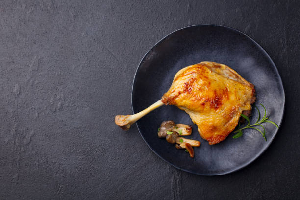 istock Duck leg confit with mushroom sauce on black plate. Slate background. Copy space. Top view. 1265530499