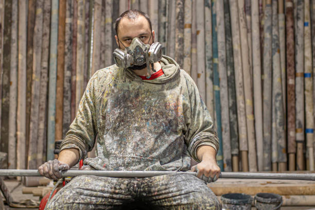 istock An artist with a crazy look and a gas mask sitting in a studio splashed with paint 1265531389