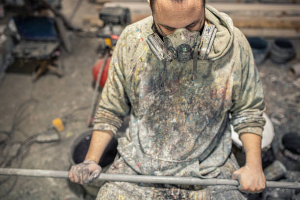 istock An artist with a crazy look and a gas mask sitting in a studio splashed with paint 1265531433