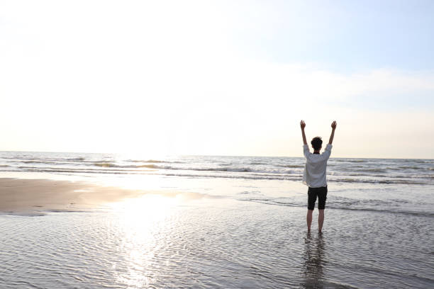 istock Asian man walking on the beach, enjoy the sunshine and wind. 1265535384