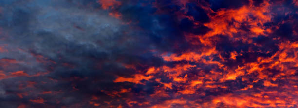 istock Sky is like a conflagration, majestic atmosphere. Blazing sky, dramatic sunset. Clouds at sunset illuminated by the sun from below, panoramic view 1265543324