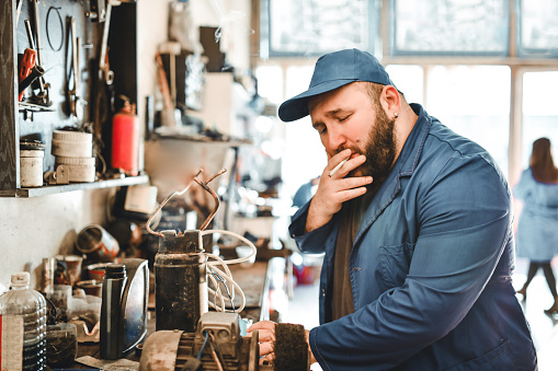 Mechanic Enjoying A Smoke While Working On Car Part