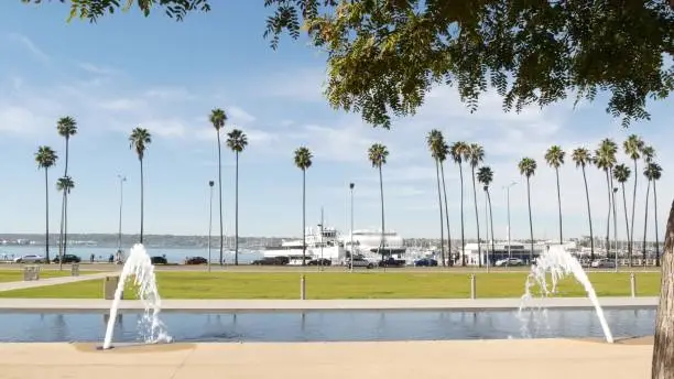 Fountain in waterfront city park near San Diego county civic center in downtown, California government authority, USA. Pacific ocean harbour, embarcadero in Gaslamp Quarter. Palms and grass near pier.