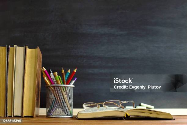 Glasses Teacher Books And A Stand With Pencils On The Table On The Background Of A Blackboard With Chalk The Concept Of The Teachers Day Copy Space Stock Photo - Download Image Now