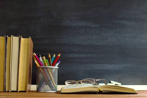 okulary podręczniki dla nauczycieli i stojak z ołówkami na stole, na tle tablicy z kredą. koncepcja dnia nauczyciela. kopiuj miejsce. - dzień nauczyciela zdjęcia i obrazy z banku zdjęć