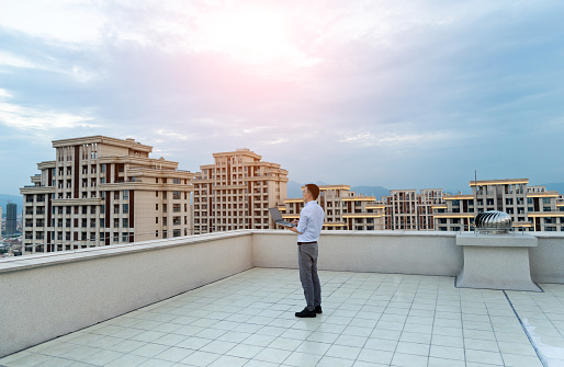 Businessman standing on the rooftop and using laptop.
