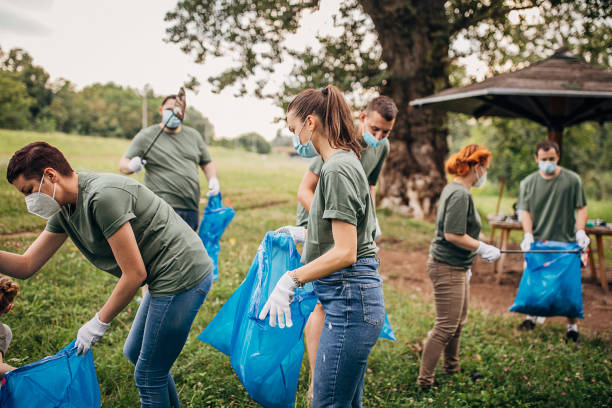 istock People with protective face masks and gloves collecting garbage from nature 1265548183