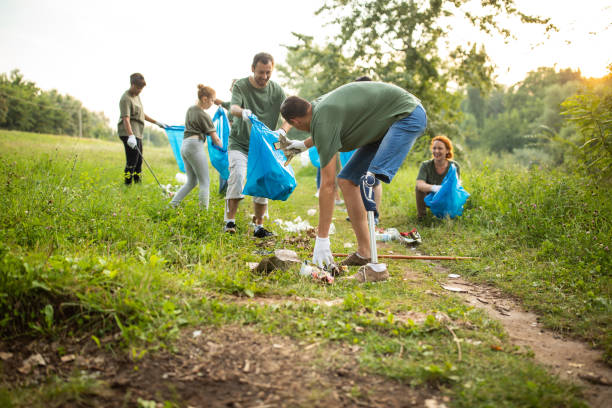 istock Man with artificial leg, cleaning environment alongside other volunteers at public park 1265548681