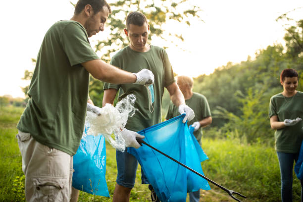 istock Environmental volunteers collecting garbage in garbage bag while cleaning public park 1265549340