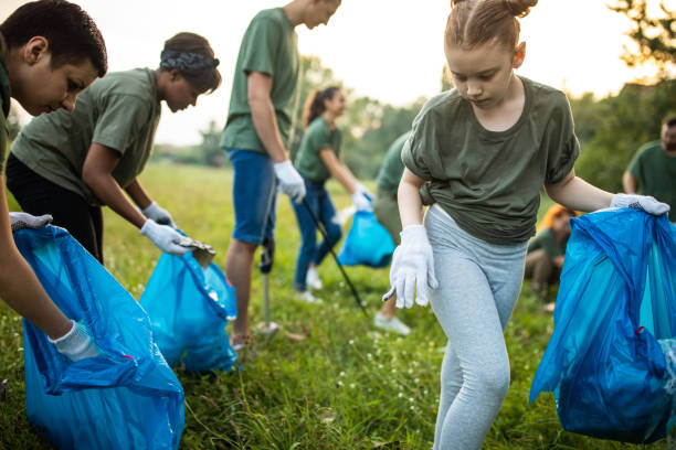 istock Environmental volunteers collecting garbage in garbage bag while cleaning public park 1265549901