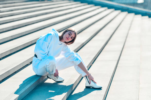 White Tracksuit Female Sitting On Steps White Tracksuit Female Sitting On Steps tracksuit stock pictures, royalty-free photos & images