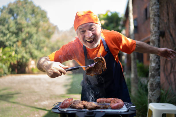 バーベキューを準備している幸せな先輩男性の肖像画 - barbecue grill chef barbecue sausage ストックフォトと画像