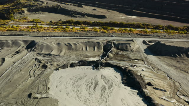 High aerial zoom out view of environmentally dangerous toxic acid mine drainage pouring into tailing dam at a mine