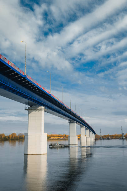 istock Sunset river gateway bridge blue sky and clouds. Autumn River bridge view. Cargo ships loading in cargo terminal on background 1265553609