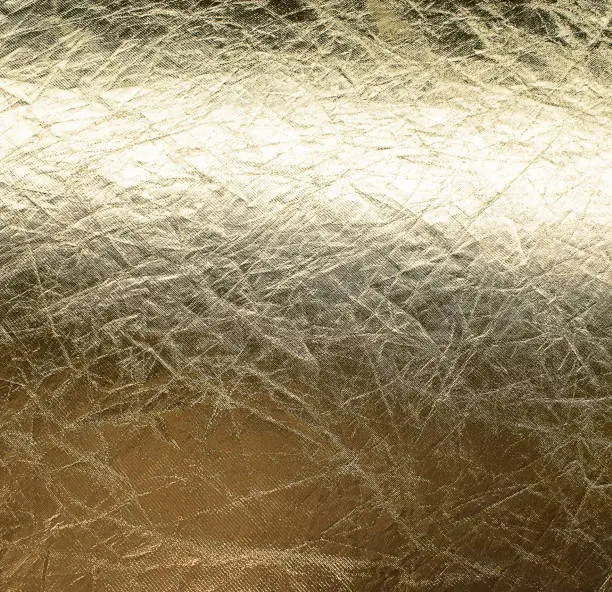 Photo of Background of old crumpled gold foil, glossy texture