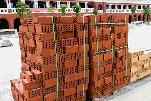 Stack of red bricks on construction site.