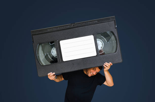 istock man holding a huge video cassette, 1265555414