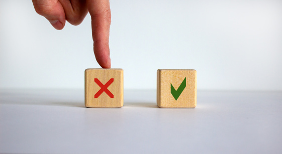 Hand making a choice between two cubes with No and Yes signs on neutral background. Business concept, copy space.