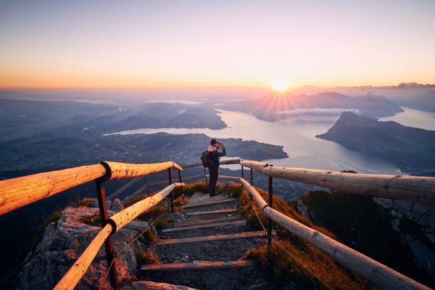 homme photographiant le paysage au beau lever de soleil - switzerland lake mountain landscape photos et images de collection