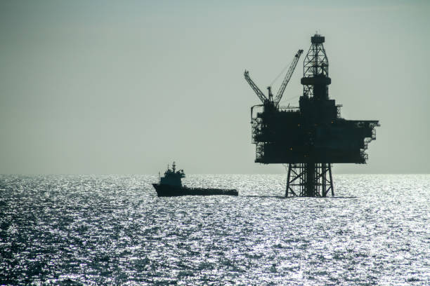 北海の石油プラットフォームリングホーンと並ぶオフショア補給船のシルエット - north sea ストックフォトと画像