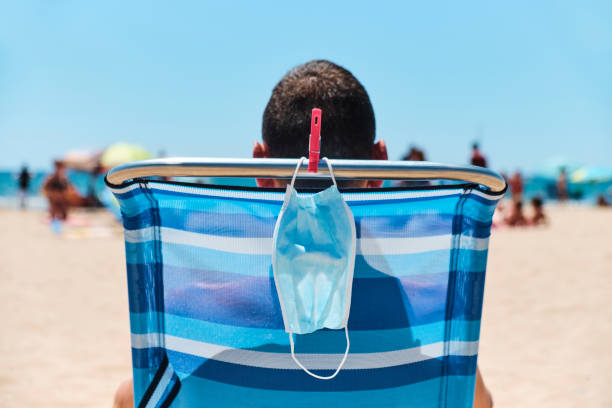 istock mask and man sitting in a deck chair on the beach 1265574651