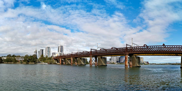 Beautiful panoramic view of a railway bridge over a river on a sunny day with deep blue sky and fluffy clouds