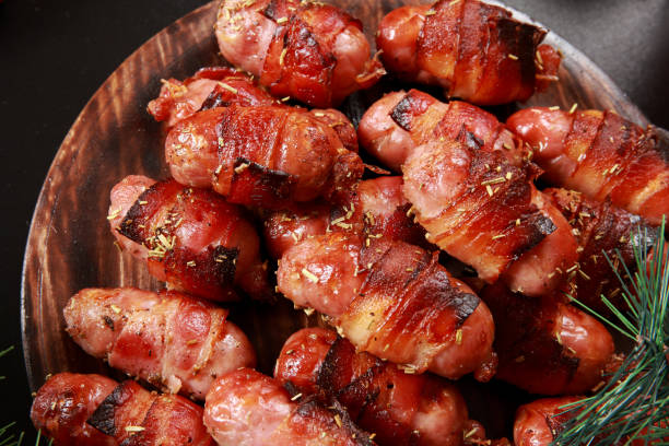 Pigs in a Blanket In the United Kingdom, "Pigs in Blankets" refers to small sausages (usually chipolatas) wrapped in bacon. They are a traditional accompaniment to roast turkey in a Christmas dinner. Marinated with a savoury sauce, also used at Parties and Events as buffet snack with cocktail sticks bacon wrapped stock pictures, royalty-free photos & images
