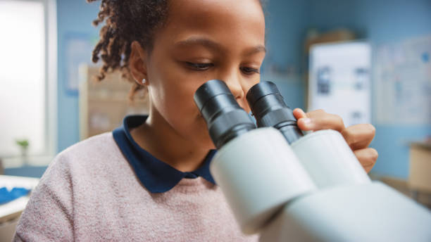 istock Portrait of Smart Little Schoolgirl Looking Under the Microscope. In Elementary School Classroom Cute Girl Uses Microscope. STEM (science, technology, engineering and mathematics) Education Program 1265582010