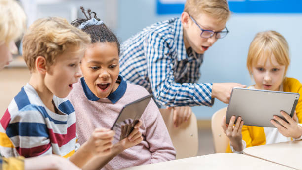 istock School Computer Science Class: Schoolchildren Use Digital Tablet Computers and Smartphones with Augmented Reality Software, They're Excited, Full of Wonder. Children in STEM, Playing and Learning 1265582148