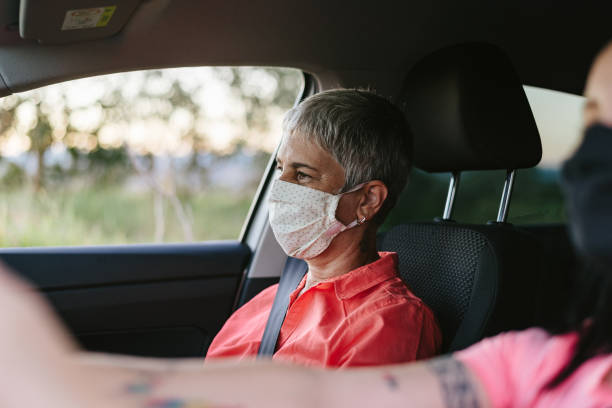 istock New normal: Woman wearing protective mask in the car 1265590532