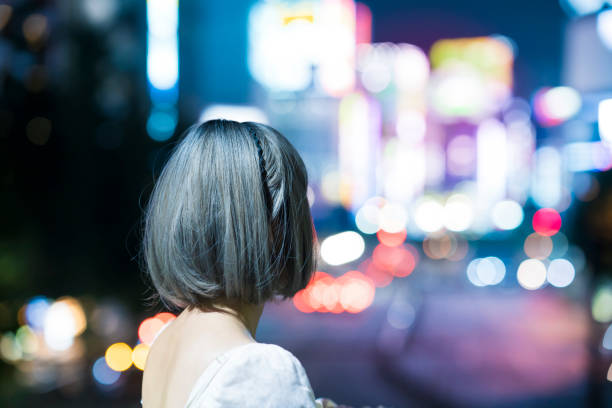 jeune femme posant dans le paysage urbain lumineux de tokyo - quartier chaud photos et images de collection