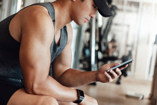 istock Muscular Young Man Training At Gym With Smart Phone 1265599596