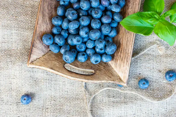 blueberries fresh and ripe in a wooden bowl / tray on a jute cloth - rustic decoration