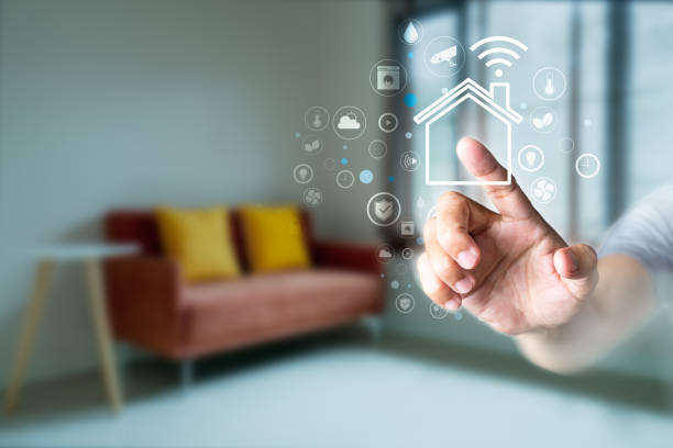 istock Man's finger touching the icons of smart home application on virtual screen with blurred room background. Home automation Concept 1265607670