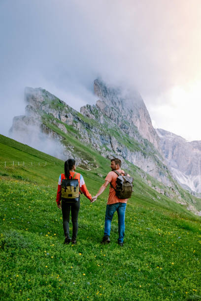 couple on vacation hiking in the Italien Dolomites, Amazing view on Seceda peak. Trentino Alto Adige, Dolomites Alps, South Tyrol, Italy, Europe. Odle mountain range, Val Gardena. Majestic Furchetta peak in morning sunlight. Italy pareja en vacaciones de senderismo en los dolomitas de italien, vista increíble en el pico seceda. trentino alto adige, alpes dolomitas, tirol del sur, italia, europa. cordillera de odle, val gardena. majestuoso pico furchetta en la luz del sol de la mañ