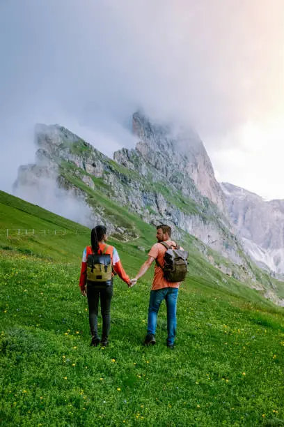 couple on vacation hiking in the Italien Dolomites, Amazing view on Seceda peak. Trentino Alto Adige, Dolomites Alps, South Tyrol, Italy, Europe. Odle mountain range, Val Gardena. Majestic Furchetta peak in morning sunlight. Italy