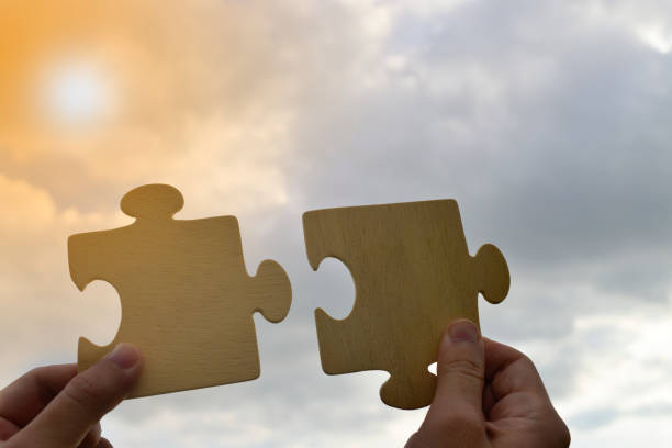 istock Close up hand of man connecting jigsaw puzzle with sunlight effect 1265610335