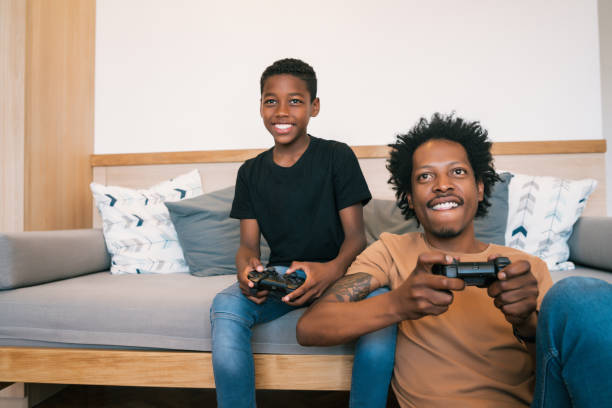 istock Father and son playing video games together at home. 1265610623