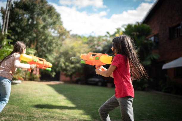 istock Sisters playing with squirt gun in the backyard 1265610952